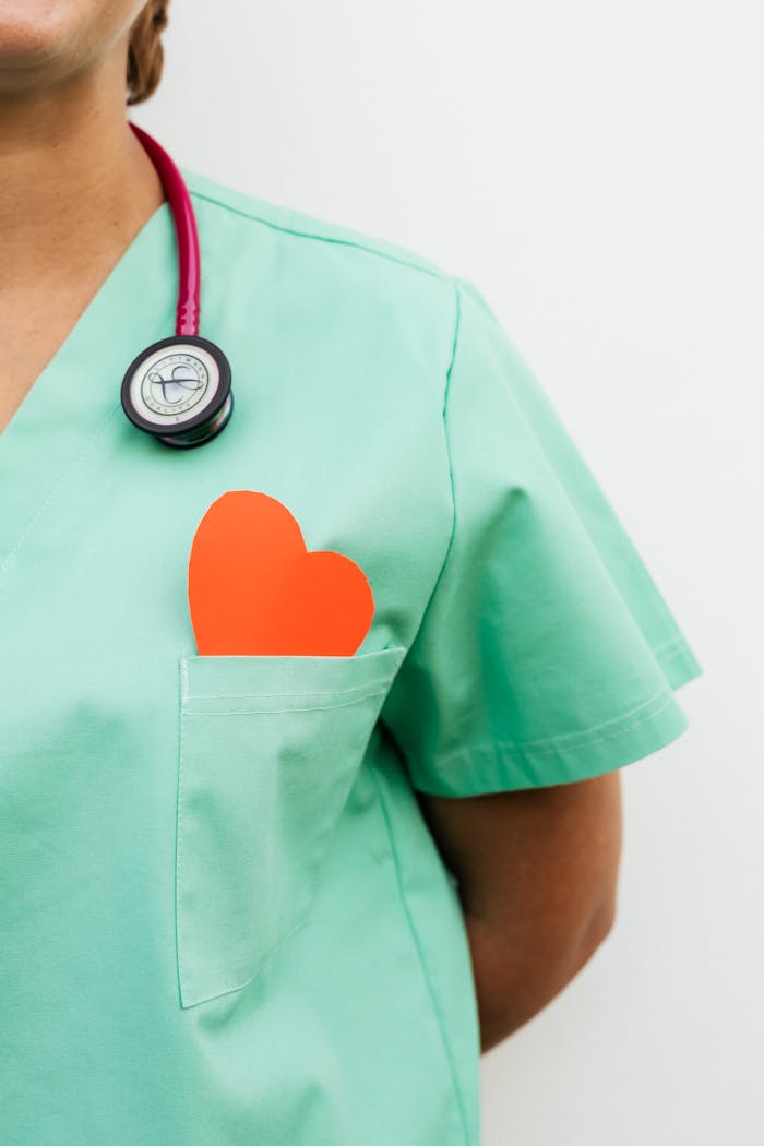 About Nurse in pastel green scrubs with stethoscope and paper heart for heart health awareness.