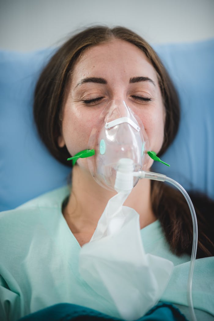 Caucasian woman in hospital bed wearing oxygen mask for medical treatment and recovery.